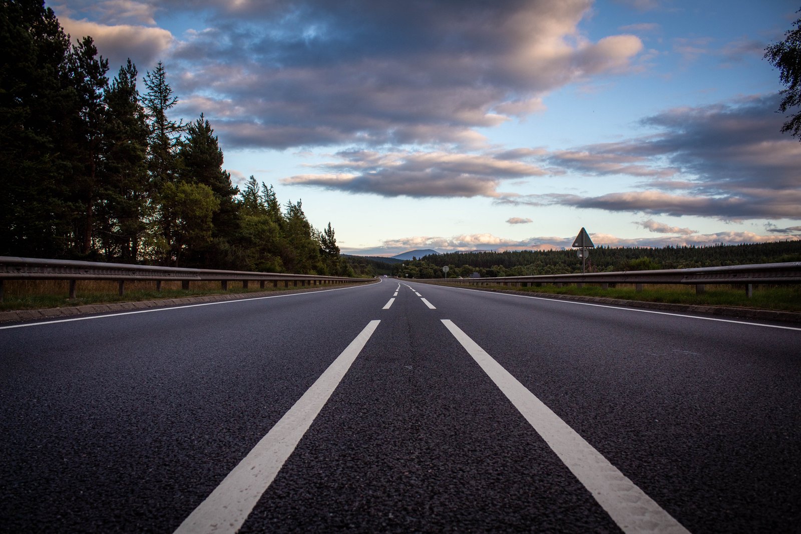 An open road through Scotland beneath an expansive evening sky